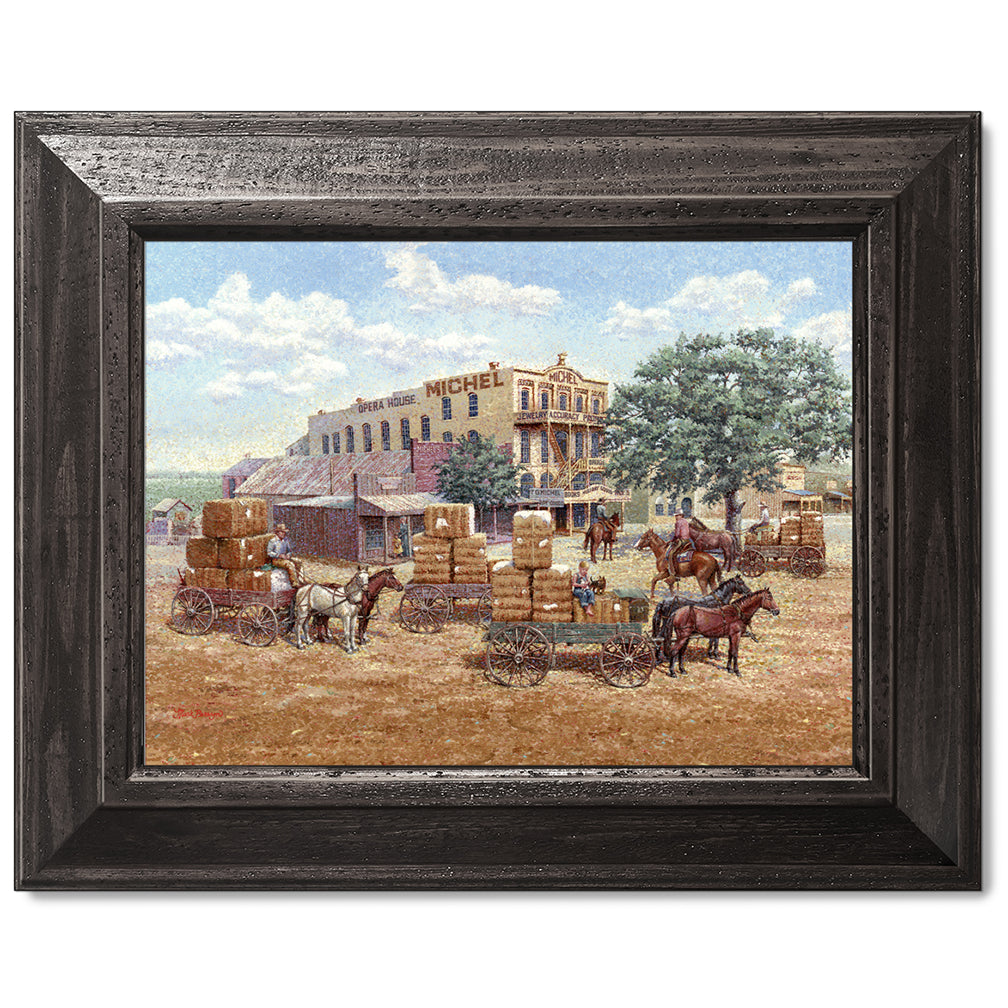 gallery wrapped print on canvas
canvas print in a black wood frame depicting a main street in a
western town with cotton wagons hauling large cotton bails