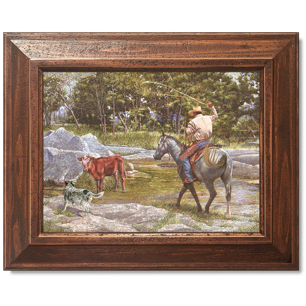canvas print in a brown wood frame depicting a cowboy on
horseback roping a calf in a creek with his blue healer dog