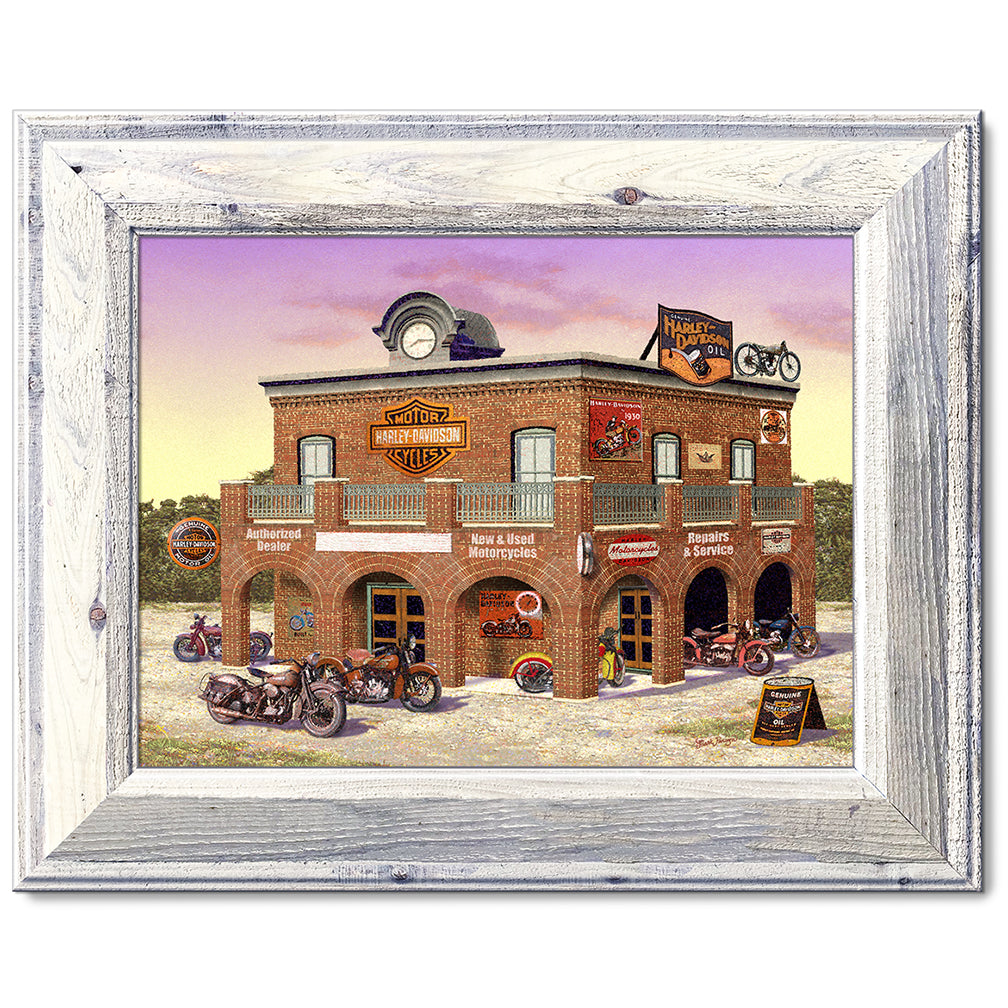 canvas print in a white wood frame depicting classic motorcycles
parked in front of a vintage harley-davidson dealership