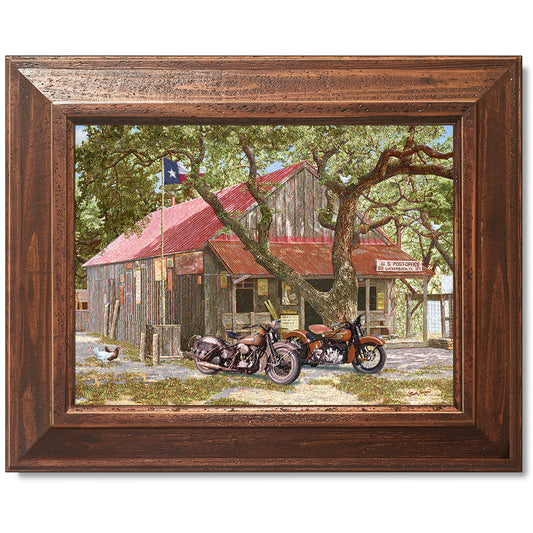 canvas print in a brown wood frame depicting classic motorcycles
parked in front of the luckenbach, texas post office
