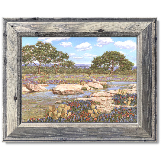 canvas print in a grey wood frame depicting a country creek
landscape with the wildflowers bluebonnets and Indian paintbrushes