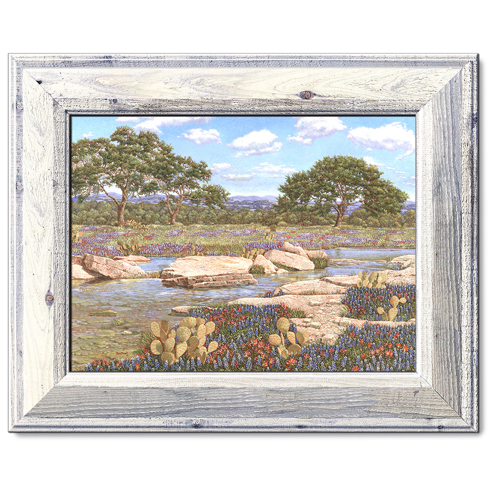 canvas print in a white wood frame depicting a country creek
landscape with the wildflowers bluebonnets and Indian paintbrushes