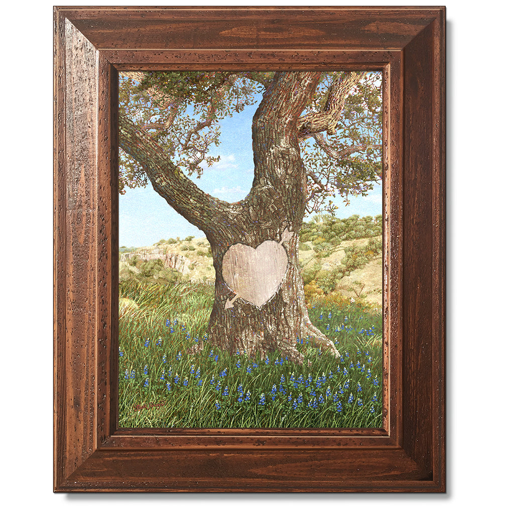 canvas print in a brown wood frame depicting an ancient oak tree
with a carved heart in a field of bluebonnets