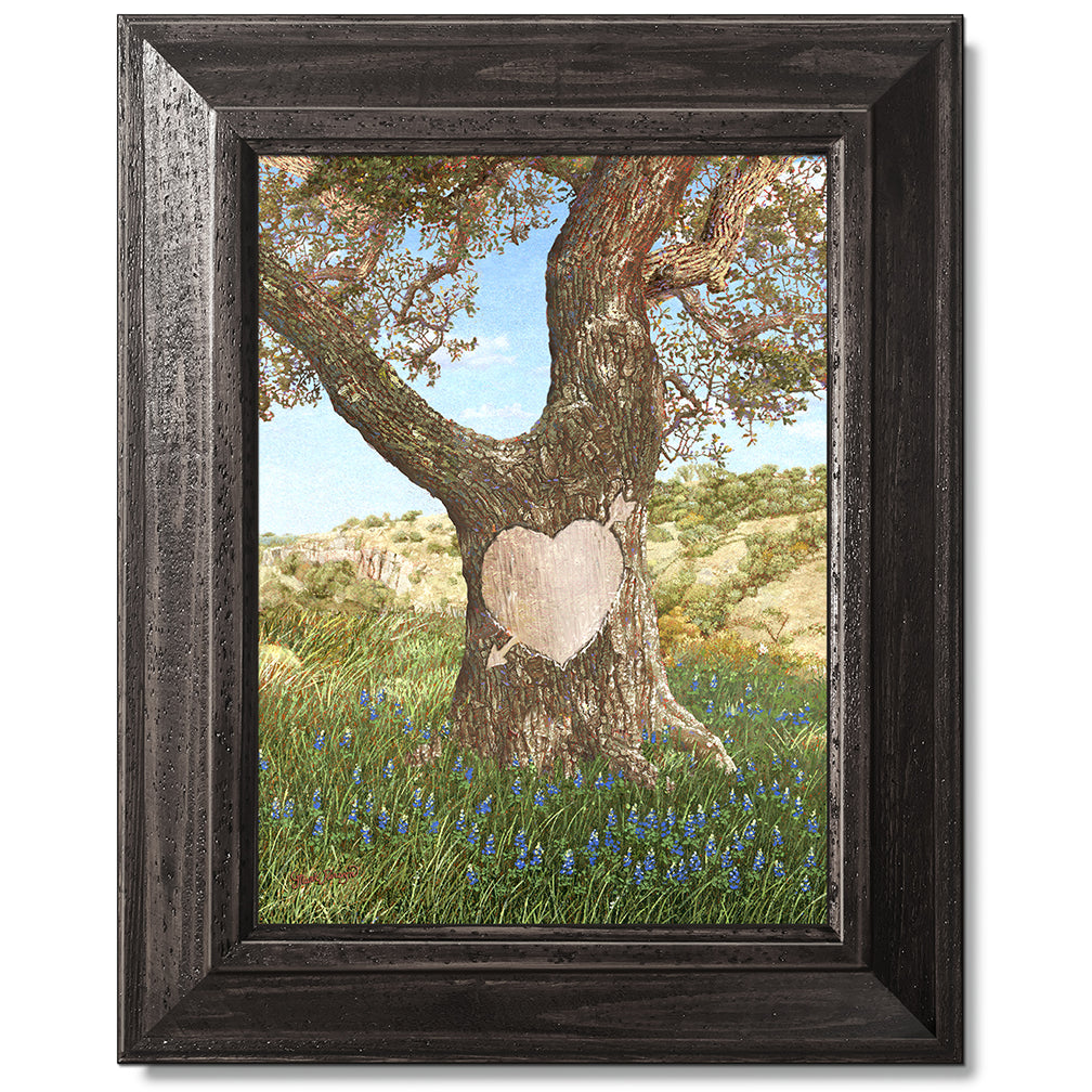 canvas print in a black wood frame depicting an ancient oak tree
with a carved heart in a field of bluebonnets