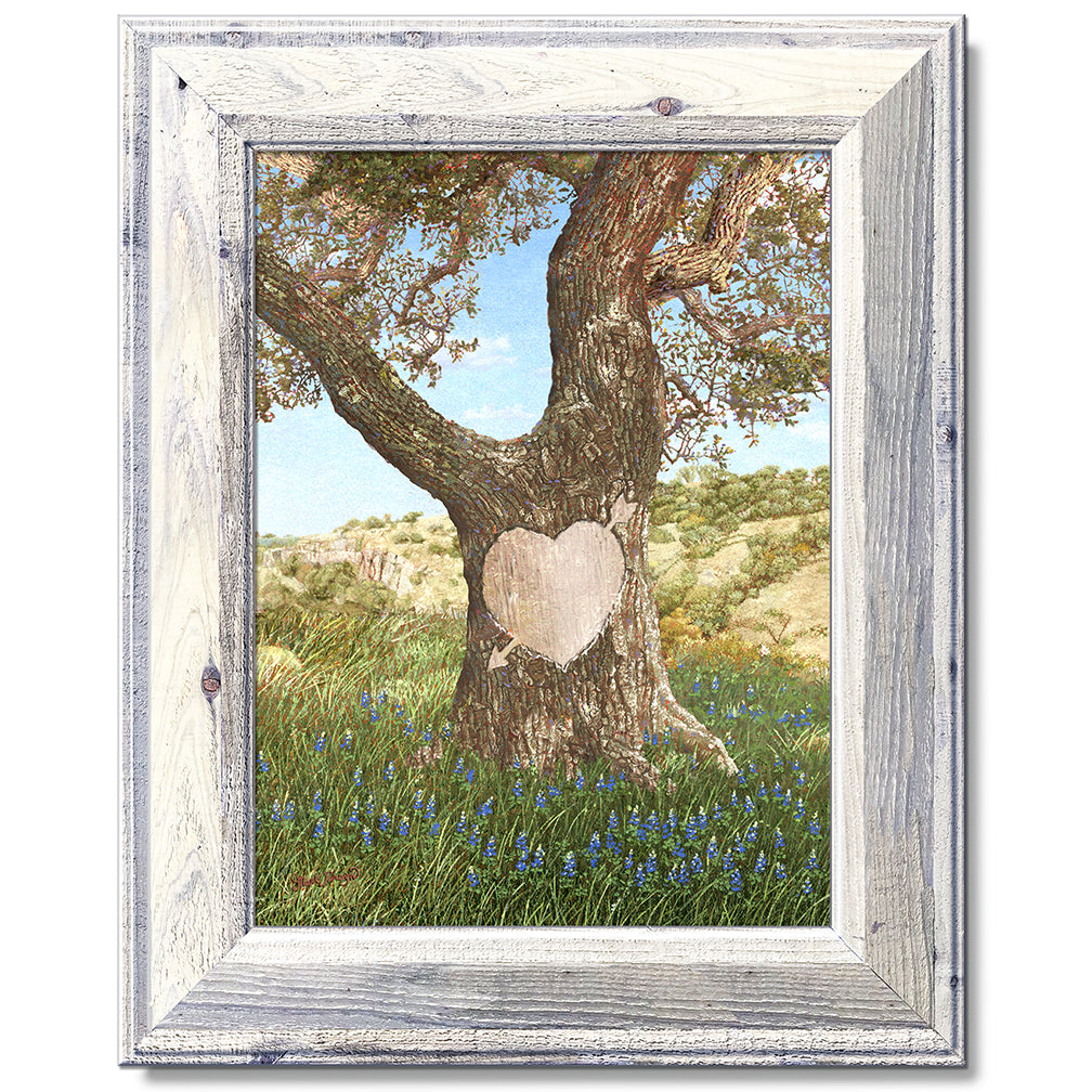 canvas print in a white wood frame depicting an ancient oak tree
with a carved heart in a field of bluebonnets