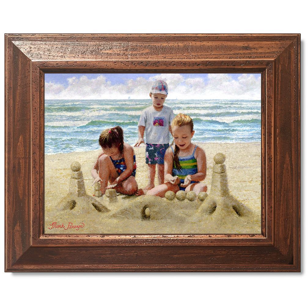 canvas print in a brown wood frame depicting children building
a sandcastle on a beach with waves in the background