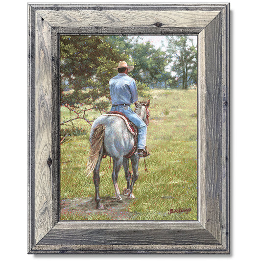 canvas print in a grey wood frame depicting a cowboy riding
away on a grey horse 