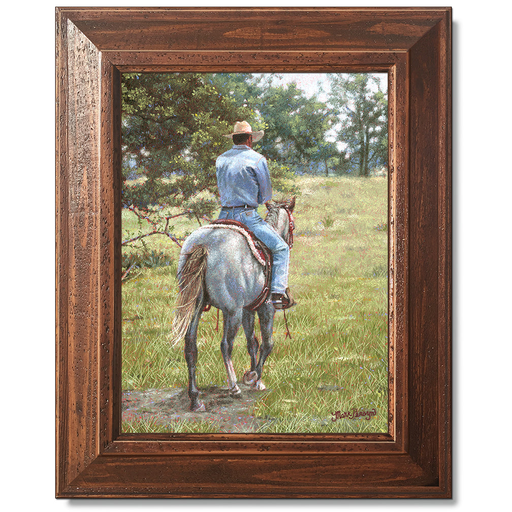 canvas print in a brown wood frame depicting a cowboy riding
away on a grey horse 