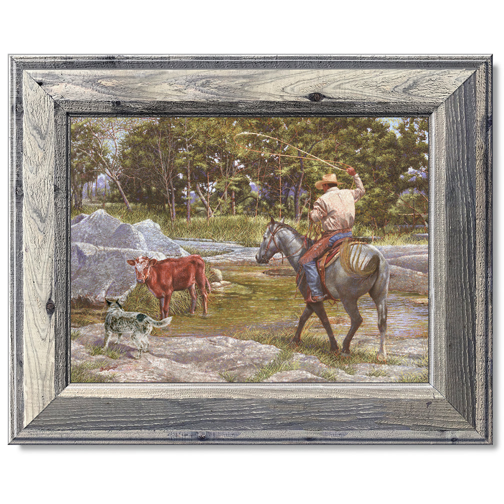 canvas print in a grey wood frame depicting a cowboy on 
horseback roping a calf in a creek with his blue healer dog  