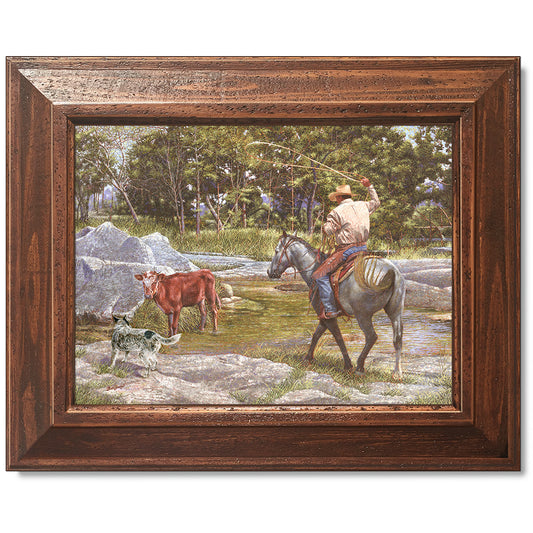 canvas print in a brown wood frame depicting a cowboy on 
horseback roping a calf in a creek with his blue healer dog  