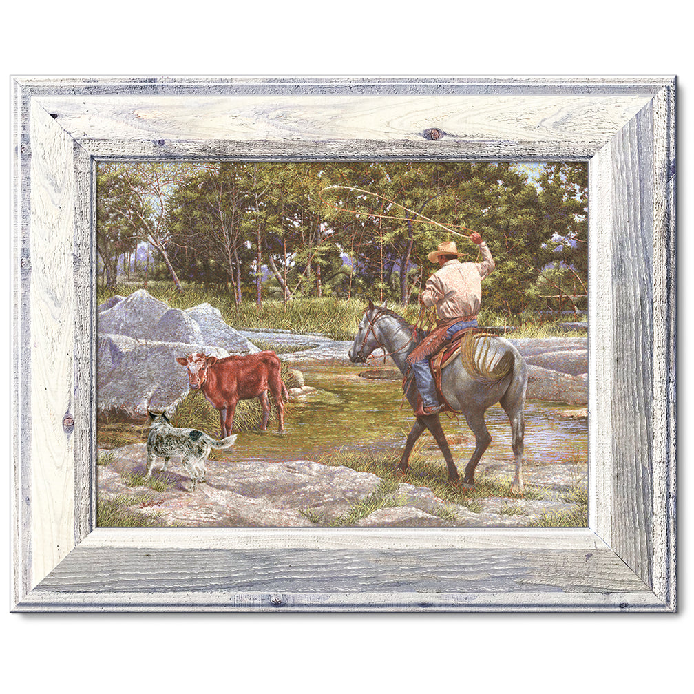 canvas print in a white wood frame depicting a cowboy on 
horseback roping a calf in a creek with his blue healer dog  