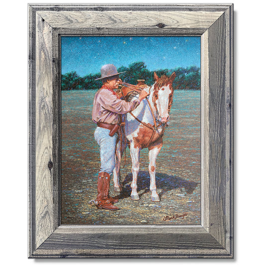 canvas print in a grey wood frame depicting a cowboy standing
beside his paint horse saddling it under a twilight sky