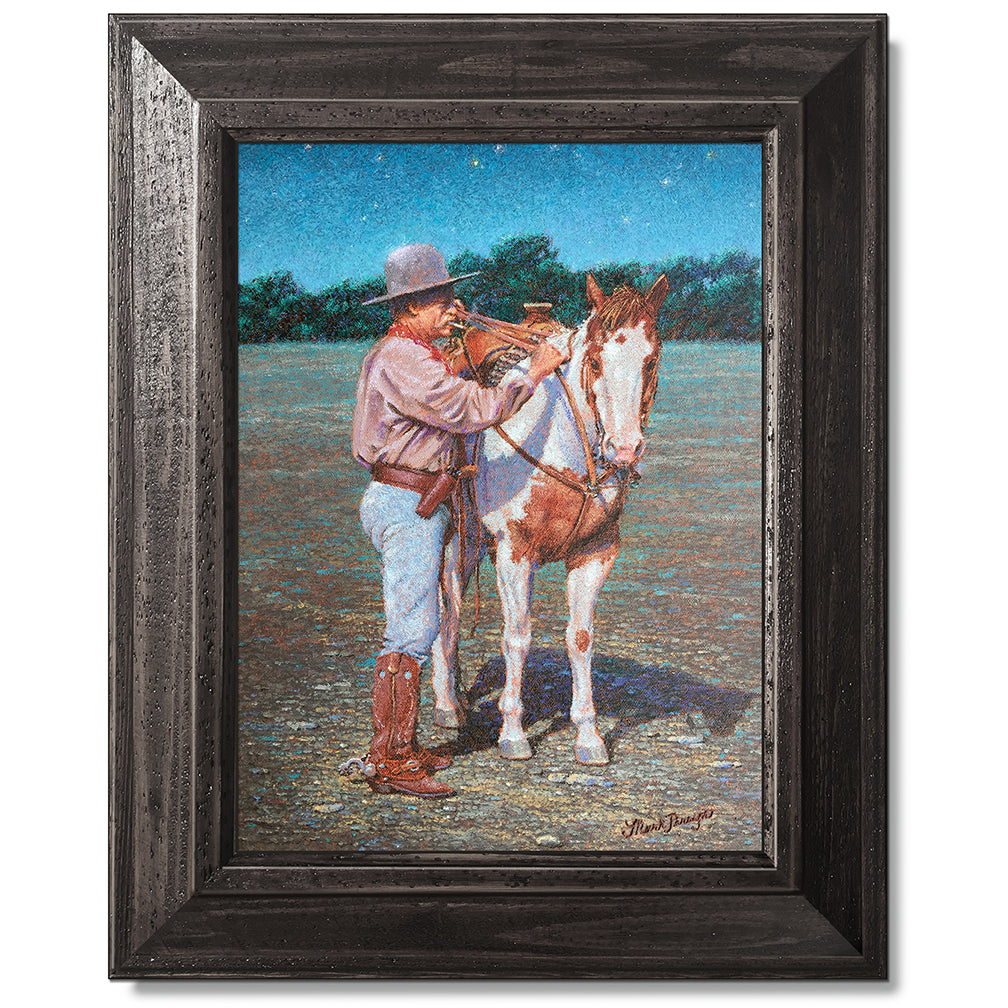 canvas print in a black wood frame depicting a cowboy standing
beside his paint horse saddling it under a twilight sky