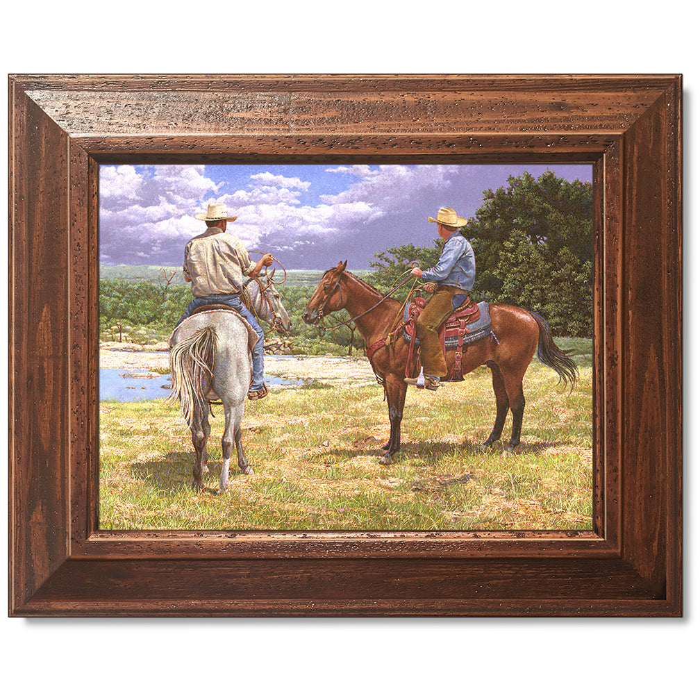 canvas print in a brown wood frame depicting a country landscape
with two cowboys on horseback watching a thunderstorm